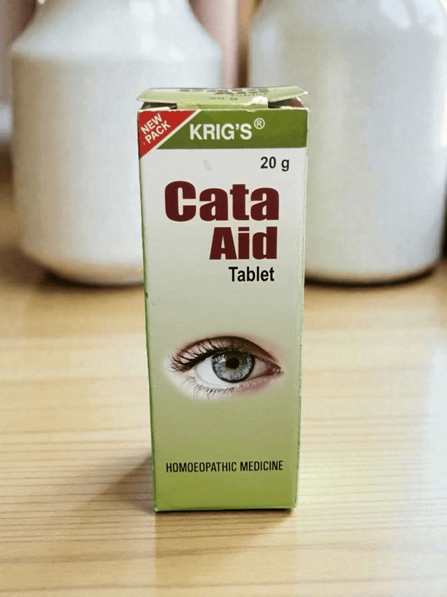 KRIG'S CATA AID TABLET HOMEOPATHIC MEDICINE 20G packaging with eye graphic on wooden surface.