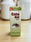 KRIG'S CATA AID TABLET HOMEOPATHIC MEDICINE 20G packaging with eye graphic on wooden surface.