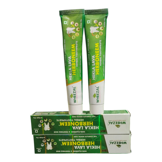 Two green and white tubes of Wheelzal Hekla Lava Herbomén herbal toothpaste standing upright on top of two matching green and white boxes against a plain white background.