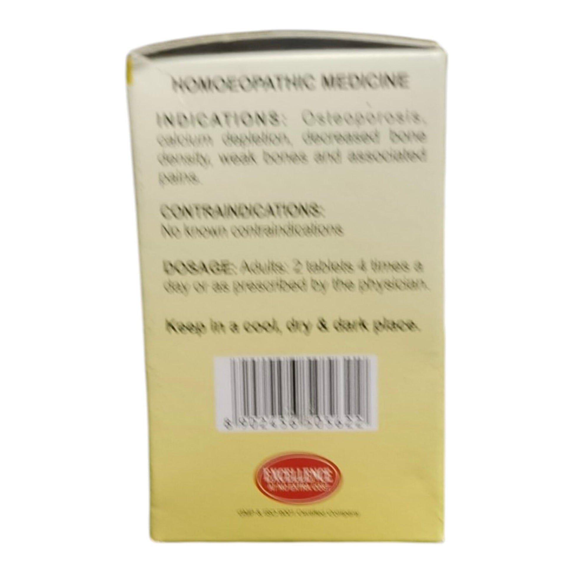 Back of a pale yellow box for a homoeopathic medicine, showing text including indications, contraindications, dosage, and a barcode, with an Excellence in Pharmacy seal at the bottom.