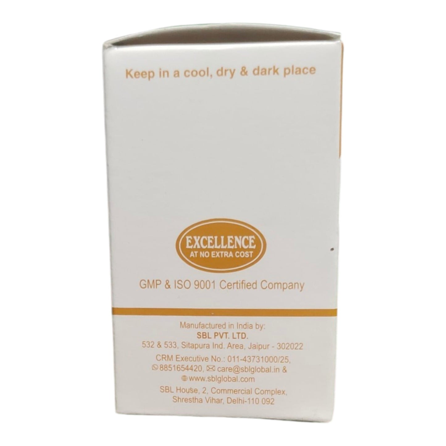 A white rectangular product box with orange text and a central oval logo reading 'EXCELLENCE AT NO EXTRA COST'. The box includes manufacturing details for SBL PVT.