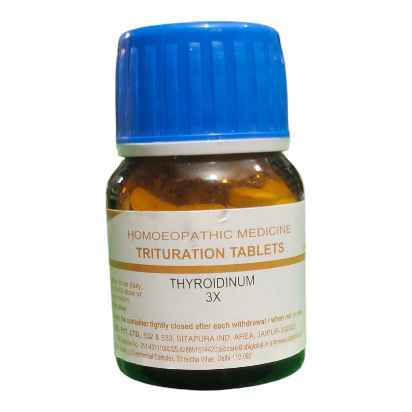 A bottle of Homoeopathic Medicine Trituration Tablets, Thyroidinum 3X, featuring an amber glass bottle, a blue cap, and a white label with gold text.