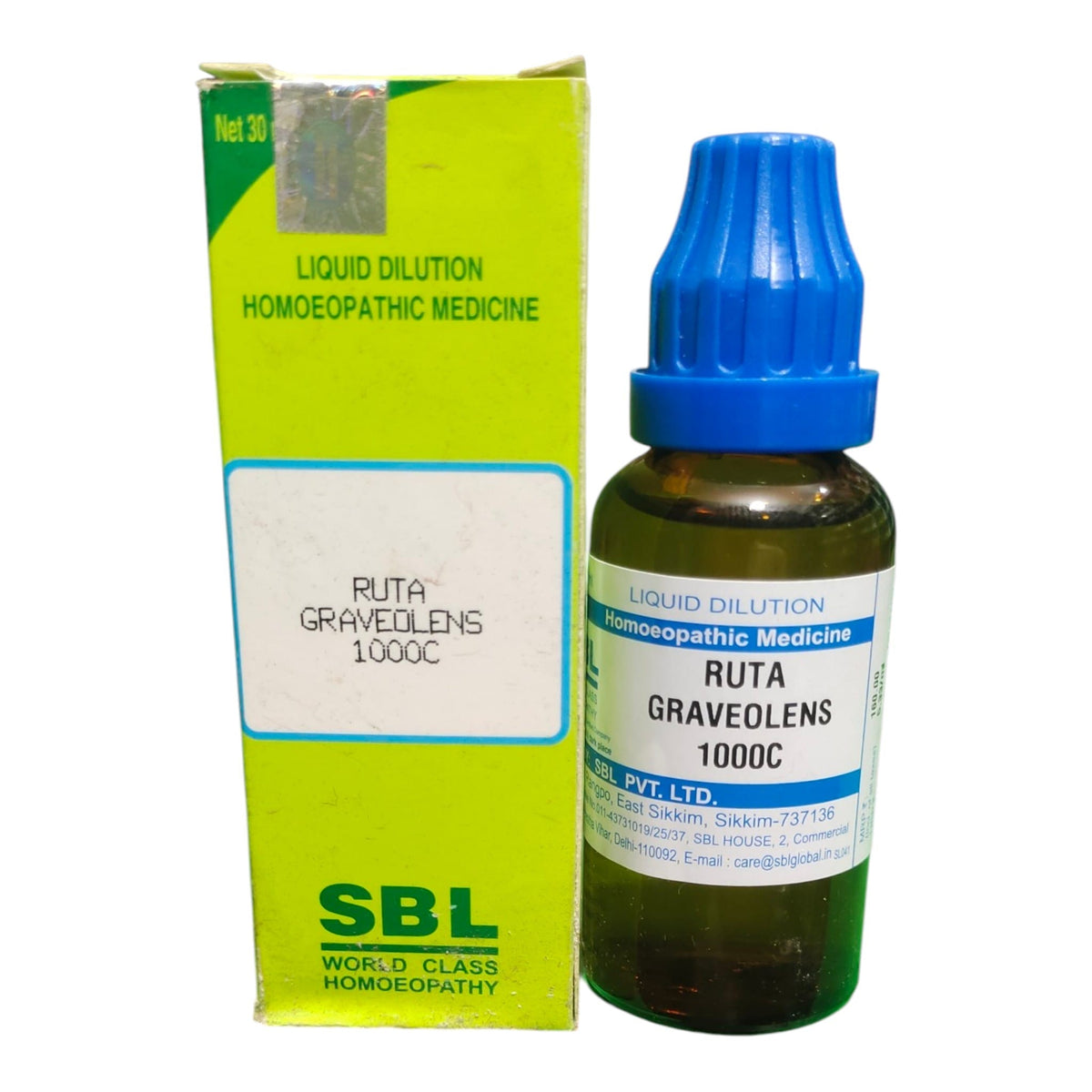 A bottle of SBL Ruta Graveolens 1000C homeopathic liquid medicine with a blue dropper cap next to its lime green cardboard packaging box.