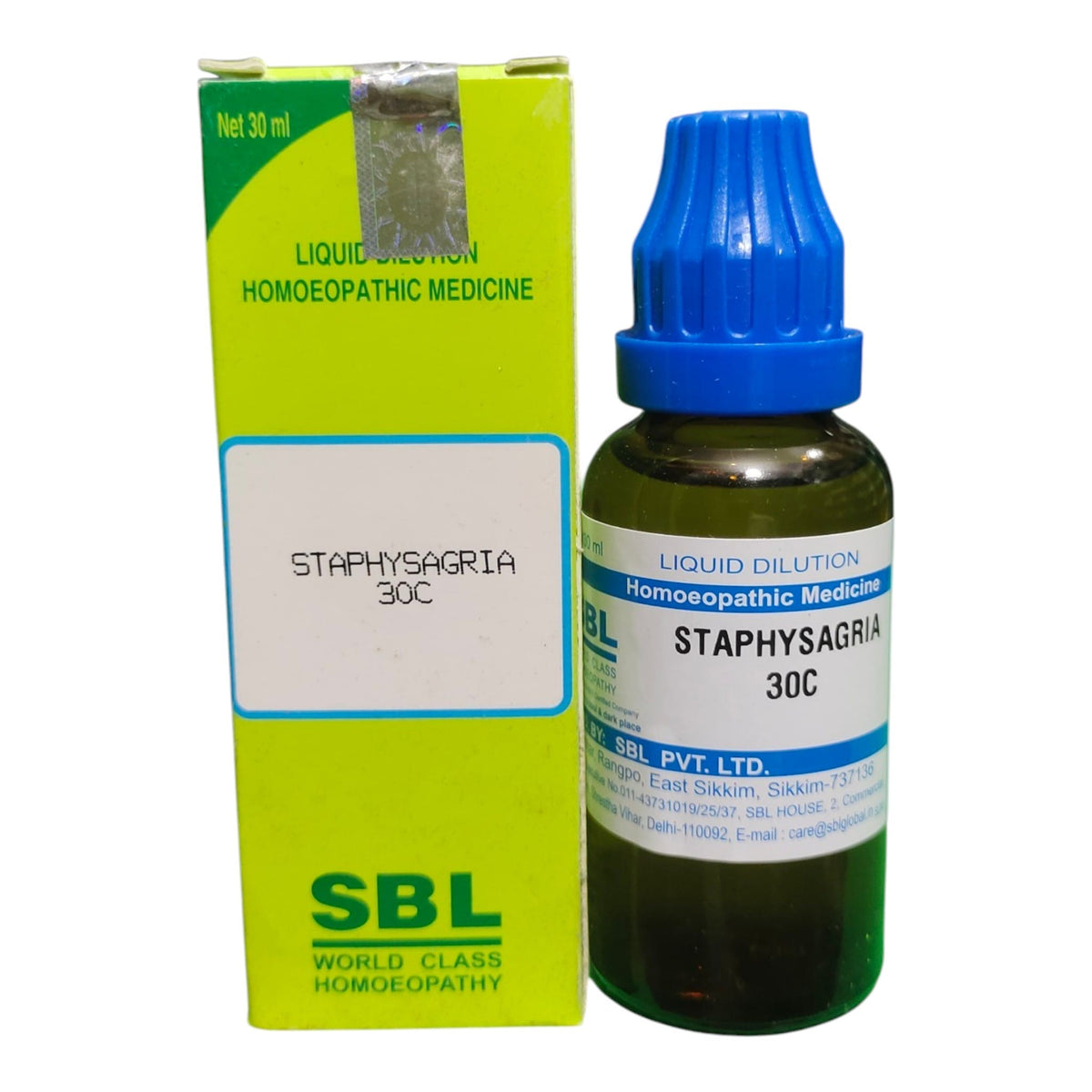 A bottle of SBL Staphysagria 30C liquid dilution homeopathic medicine next to its lime green and white cardboard packaging box, on a plain white background.