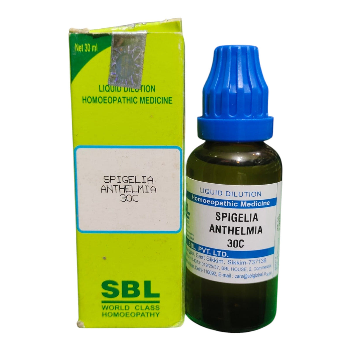 A bottle of SBL Spigelia Anthelmia 30C homeopathic liquid medicine next to its lime green and white cardboard packaging box, on a plain white background.