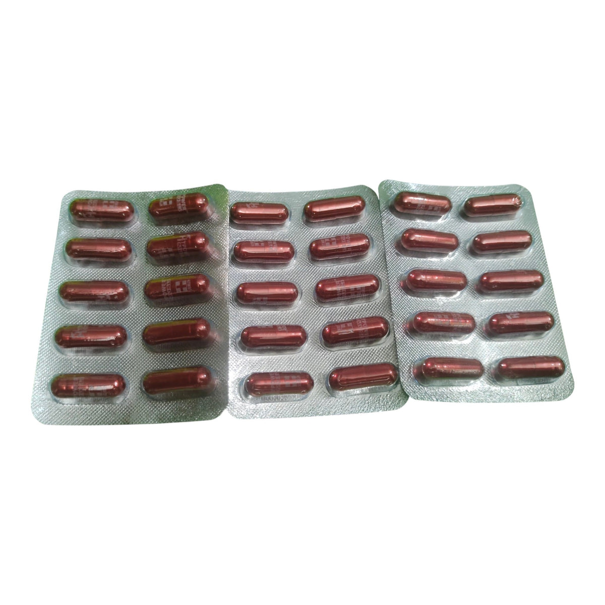 Three blister packs containing reddish-brown oval capsules, arranged side by side on a plain white background.