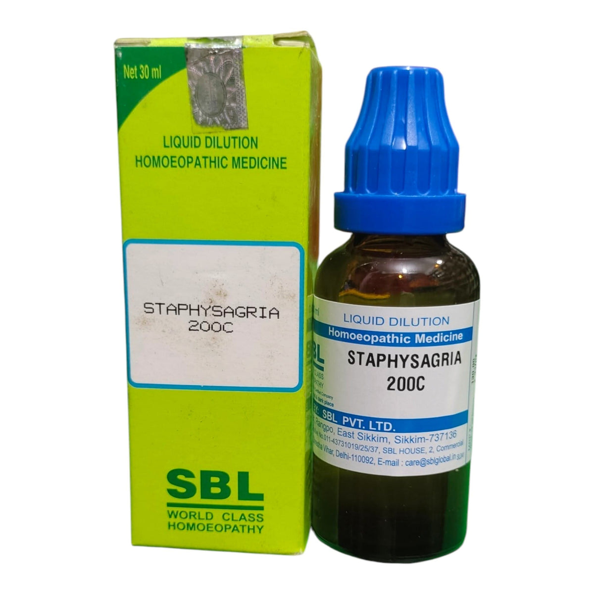 A bottle of SBL World Class Homoeopathy Staphysagria 200C liquid dilution medicine next to its lime green cardboard box, on a plain white background.