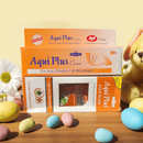 Aqui Plus cream boxes on a wooden surface with Easter eggs and a teddy bear.